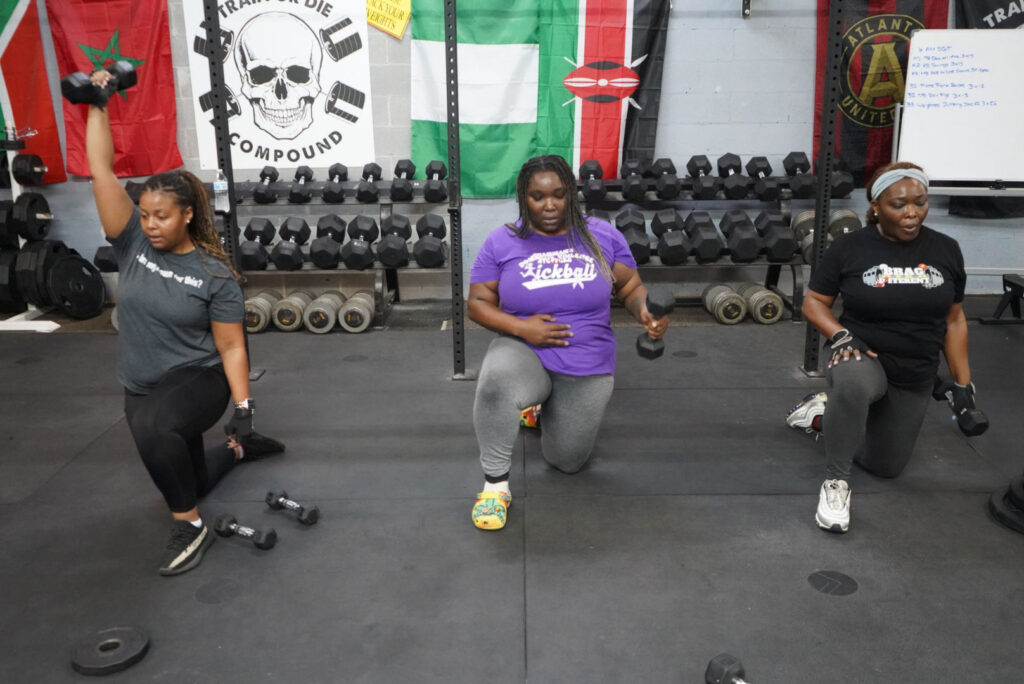 Small group training with three strong women lifting weights.